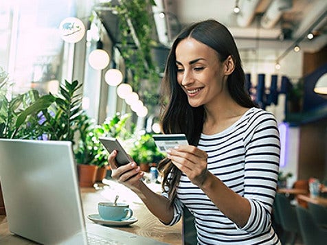A woman holding a credit card and looking at her mobile