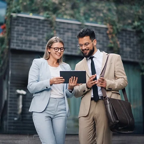 A man and woman are collaboratively holding a tablet computer