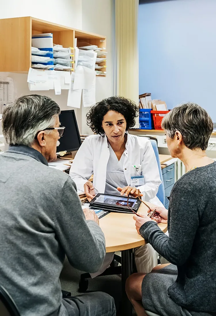 A doctor converses with a patient in a hospital room, discussing treatment options and care plans