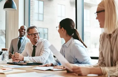 A group of people sitting at a table, smiling and in discussion.