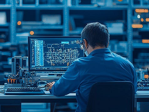 Backview of a man on his computer looking at monitor.