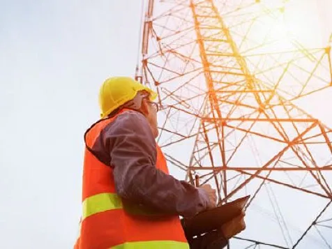 A man working at the site near a transmission tower