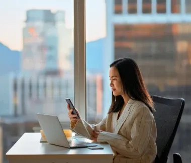 woman working at a desk holding a mobile