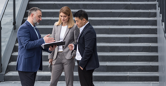 Two male and a female colleague having a discussion and looking at a tablet.