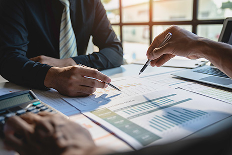 Two colleagues having a dicussion with pencils pointing to graph on desk.