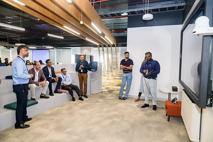 Man showing several colleagues something on a large screen
