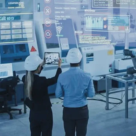 Two colleagues in hardhat looking at computerized screen.