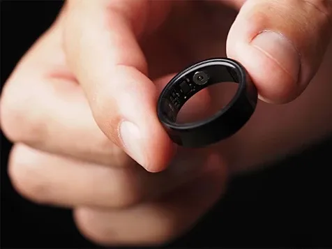 A person holds a black ring inscribed with the word "love," showcasing a simple yet meaningful piece of jewelry.