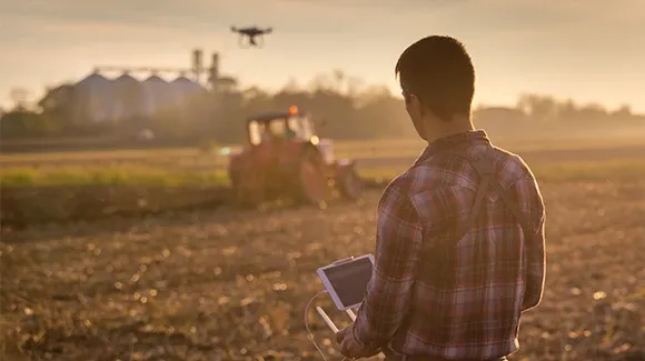 A person flying a drone over agricultural land