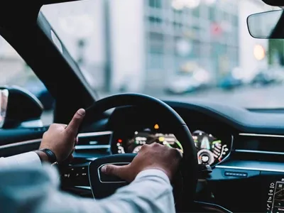 View of a man hands on the steering wheel of a car.