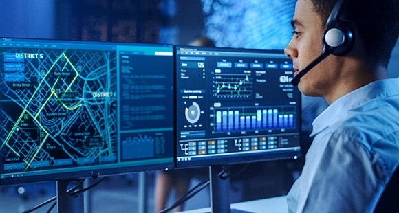 A man on headphone looking at computer screen