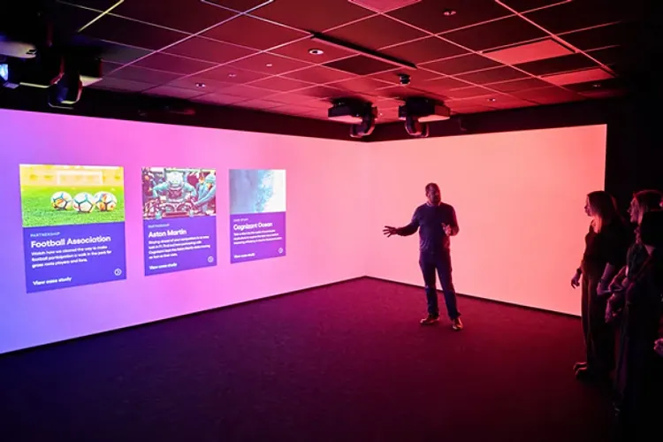 Several individuals gather in front of a large screen