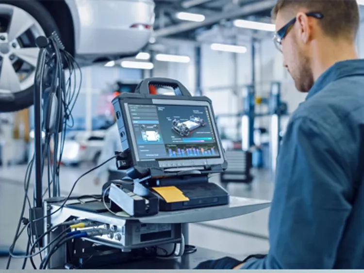 An auto mechinic looking at laptop screen.