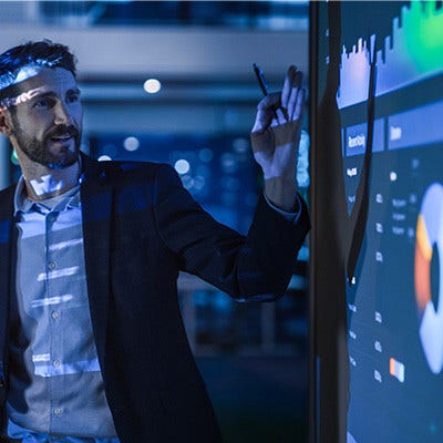 A man giving a presentation while looking at charts.