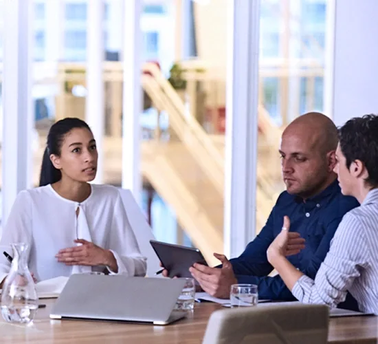 A group of three professionals in a server room discuss work