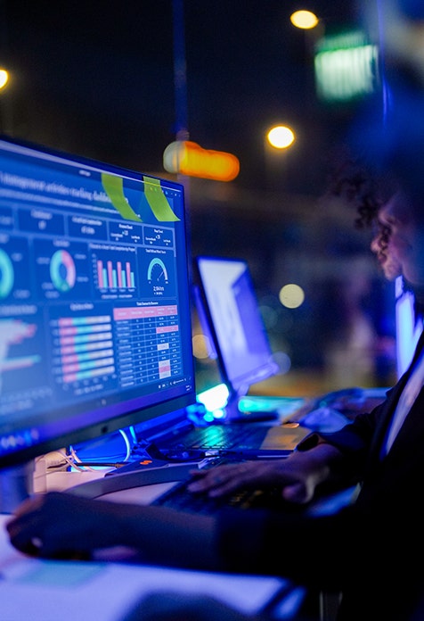 Person working on computer with data dashboards at night