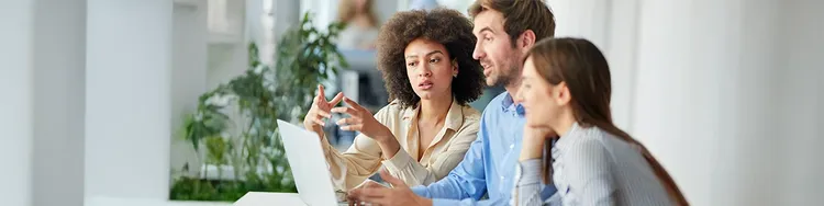 Three colleagues looking into a laptop and having a discussion