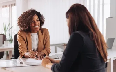 Two women sitting and smiling at eachother