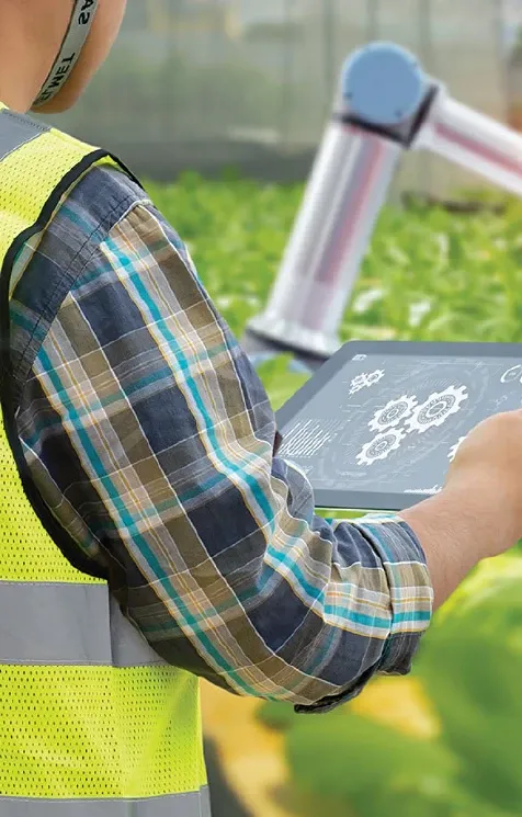 A man working in the field, looking at gears on a tablet screen