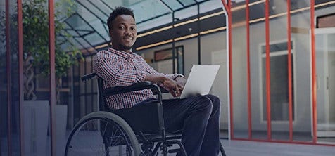 A man sitting in a wheelchair balancing a laptop on his thighs