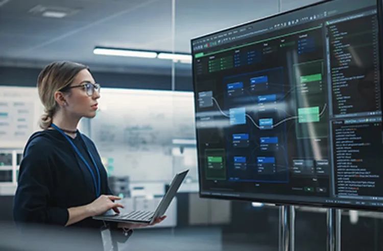 A woman in a business suit gazes intently at a large screen displaying data or information.