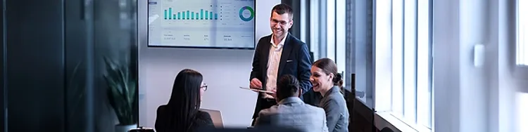 Professionals meeting in office reviewing dashboard charts on wall screen