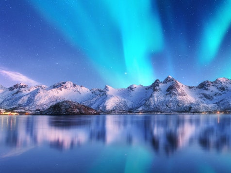 A water-body framed by a mountain rangebehind it, against a beautiful blue sky.