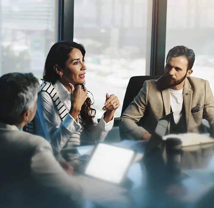 A diverse group of people engaged in discussion around a conference table.