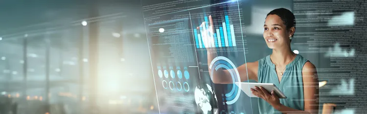 A woman using a tablet while interacting with a futuristic data dashboard and charts interface