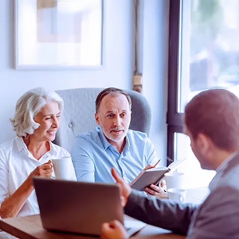 A midaged couple looking at laptop presented by a representative