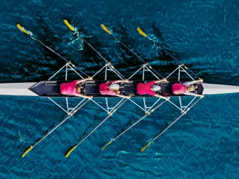 Aerial view of four rowers in perfect synchrony, symbolising unified marketing orchestration.