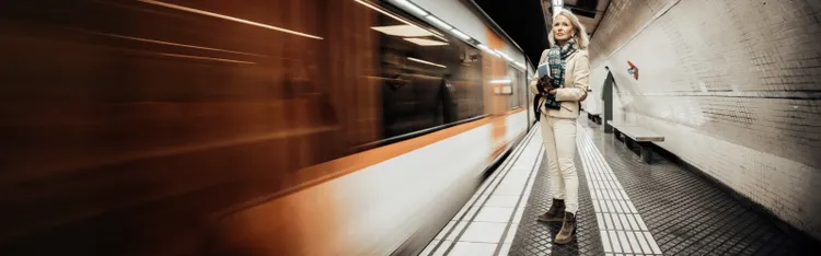 Woman standing on subway platform as train speeds past